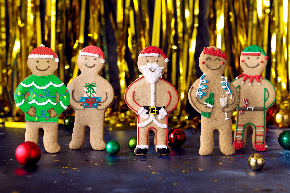 Festive gingerbread family lineup with Christmas decorations, perfect for personalized gifts from Biscuiteers this holiday season.